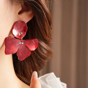 Close-up of elegant red marble resin flower earrings with sparkling rhinestones on model
