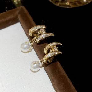 Macro shot of 14K gold plated H-letter earring with sparkling zircons and white pearl drop