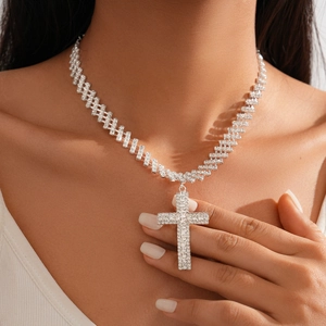 Gros plan d'un pendentif croix argenté serti de diamants porté avec élégance par un mannequin