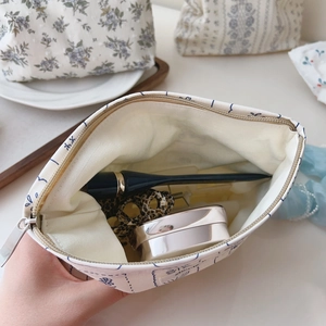 Detail showing the large capacity of a white canvas makeup bag with blue patterns