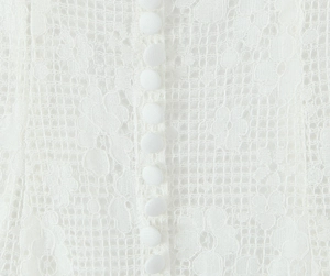 Close-up of intricate white plum lace fabric with elegant cloth-wrapped buttons