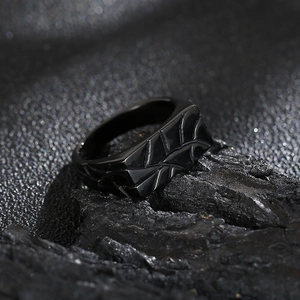 Macro shot of black geometric men's ring with a sleek matte finish on dark textured rock