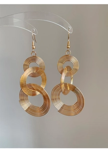 Macro shot of gold-tone multi-layered coiled metal hoops in a triple nested earring design