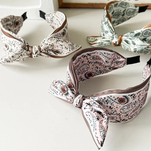 Close-up of three Paisley print bow headbands in pink, cream and green fabric