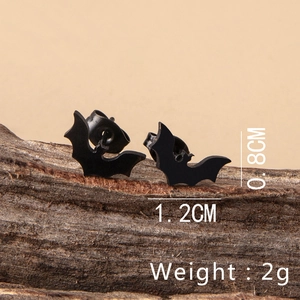 Detail view of black bat stud earrings with size and weight measurements on wood surface