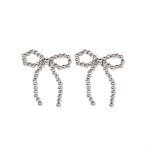 Detailed close-up of shiny silver beaded bow earrings with faux pearl accents