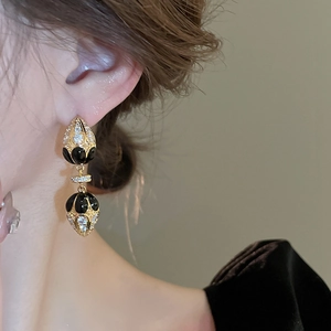 Detailed view of French vintage gold plated teardrop earrings with black enamel and zircon