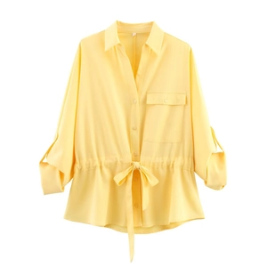 Detail of yellow long sleeve shirt featuring a drawstring waist and front flap pocket