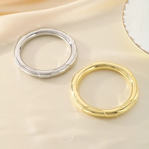 Close-up of gold and silver hollow chunky bangles on elegant beige silk background