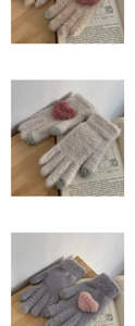 Detail of plush knitted mittens with heart patches and contrasting color fingertips