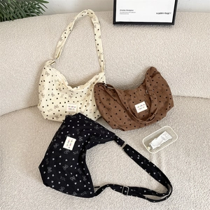 Close-up of corduroy shoulder bags with heart and bow prints on a cozy cream sofa