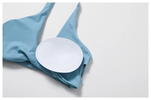 Detail of light blue yoga top featuring removable white circular bra pads and smooth knit