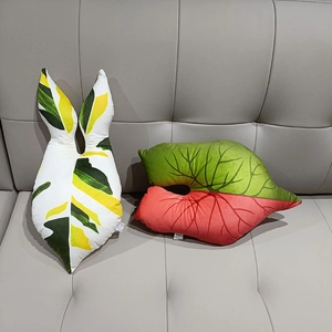 Plush leaf shaped decorative pillows in heart and long styles on a grey leather sofa