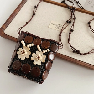 Détail du sac artisanal en coque de noix de coco avec fleurs beige et bandoulière