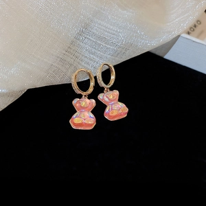 Gros plan sur les créoles dorées avec pendentifs ours rose aurore et accents de zircon