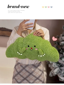 Macro detail of soft fruit green plush croissant pillow with cute embroidered face held by model
