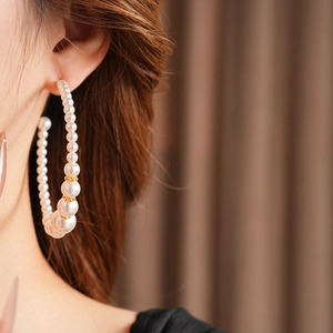 Primer plano de una modelo con pendientes de aro grandes de perlas doradas de estilo vintage