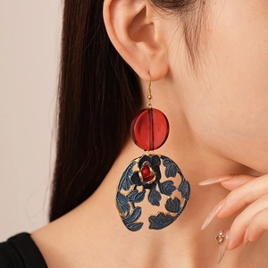 Detailed view of vintage flower earrings with red beads and blue enamel patterns
