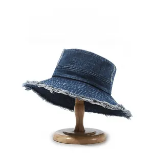 Close-up of frayed edges and stitching detail on washed dark blue denim bucket hat