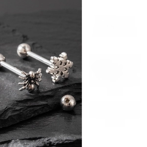 Macro detail of snowflake and spider stainless steel ear studs with screw ball backs