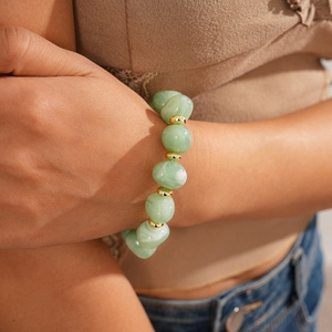 Macro detail of green oval resin beads with gold metal spacers on a vintage necklace