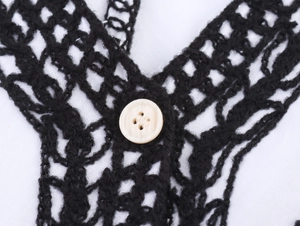 Close-up of black hollow crochet knit fabric with a white round button detail
