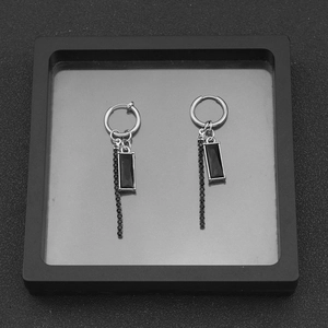 Macro shot of silver earrings with black rectangular gemstones and long beaded tassels