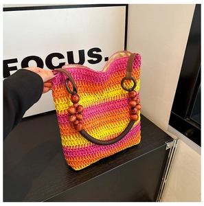 Detail of colorful rainbow straw tote bag featuring natural brown wooden bead handles