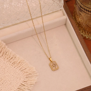 Close-up of golden necklace with a rectangular starburst pendant on a velvet box