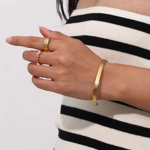 Detail shot of hammered 18K gold plated stainless steel cuff and rings on a model