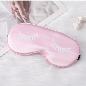 Close-up of pink satin sleep mask with eyelash print on white plush texture background