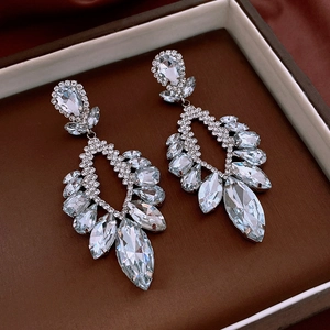 Macro detail of silver drop earrings with multi-cut rhinestones in a luxury jewelry box