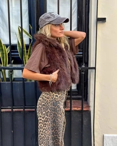 Detail shot of brown faux fur vest styled with leopard print pants and casual cap