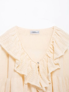 Detail view of cream knit sweater showing V-neck lace hollow crochet ruffle and small buttons