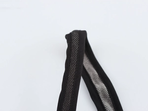 Detailaufnahme eines schwarzen Trägers mit reflektierender silberner Textur auf dem Kleid