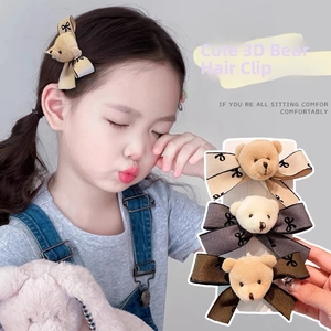 Close-up of plush bear hair clips with printed bows in earthy khaki and brown colors