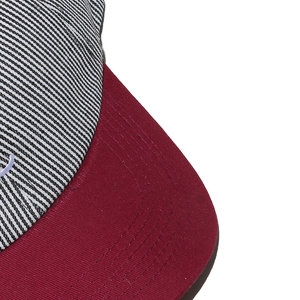 Gros plan de la casquette rayée montrant les coutures et la visière bordeaux