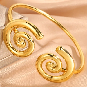 Polished gold stainless steel open bangle with elegant double spiral design on silk