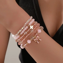 Primer plano de conjunto de pulseras de cuentas rosas con trébol de corazón en la muñeca