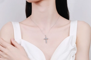 Close-up of S925 sterling silver cross necklace with pavé moissanite on a model
