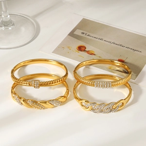 Detail of four 18k gold plated stainless steel bracelets with pavé diamonds on a white surface