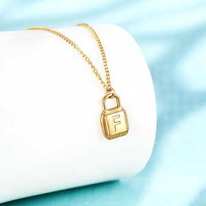 Detailed macro view of the golden letter F padlock pendant hanging on a clean white stand