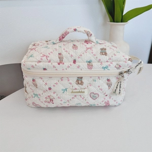 Detail of white quilted cosmetic bag with cute cartoon bear and floral patterns
