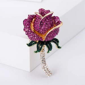 Dettaglio della spilla a rosa con strass magenta e verdi incastonati in metallo dorato