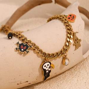 Detailed close-up of 18K gold-plated charms including pumpkin and skull on a Cuban chain