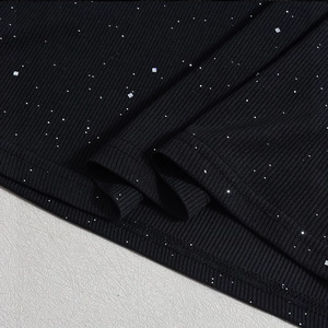 Close-up of black ribbed dress fabric with silver glitter details and fine stitching