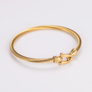 Detail eines goldenen Hufeisen-Kabelarmbands mit gedrehtem Seildesign auf weißem Hintergrund