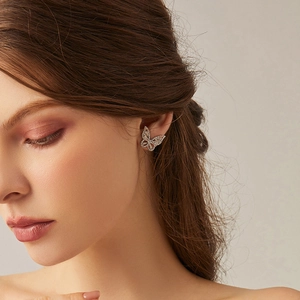 Élégante boucle d'oreille papillon en argent avec zircons brillants portée par un modèle