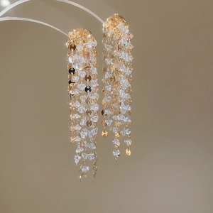 Close-up of 18k gold plated tassel earrings with sparkling crystals and metal sequins