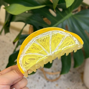 Handheld lemon slice acrylic hair claw clip with vibrant yellow and white details